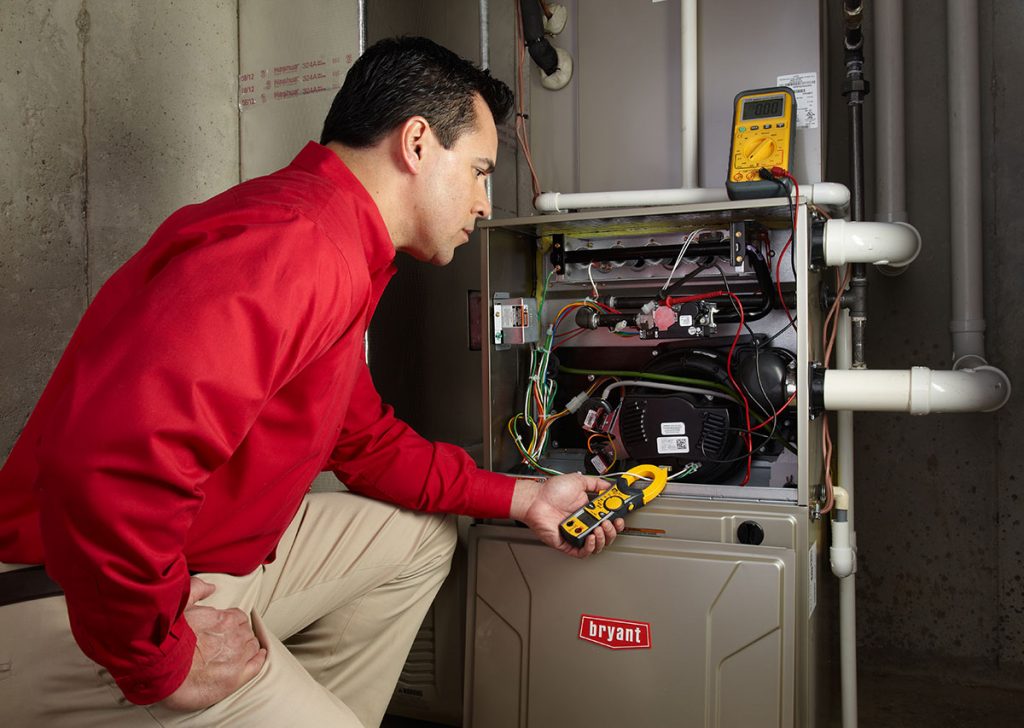 Heating and air conditioning technician servicing an indoor furnace in Aurora, CO
