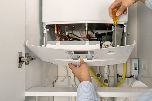 HVAC technician repairing an indoor boiler in Aurora