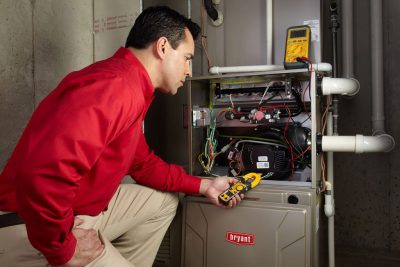 Heating and air conditioning technician servicing an indoor furnace in Aurora, CO